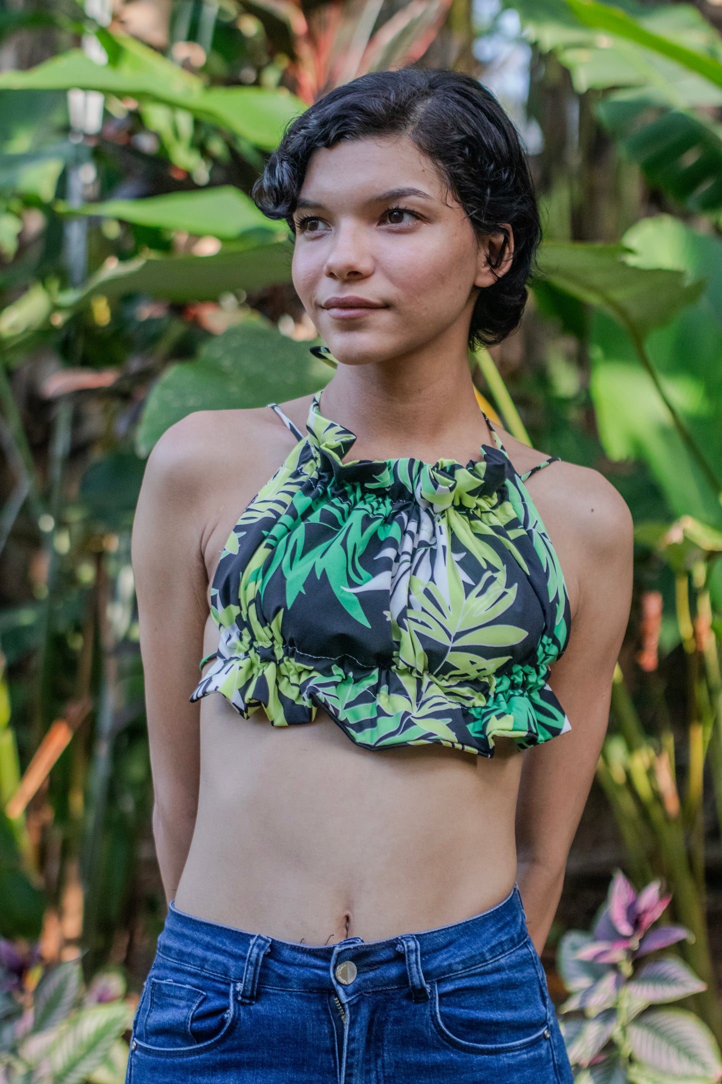 Mujer vistiendo un scrunchy Top con estampado tropical en verde es el complemento perfecto para un look fresco y lleno de vida. Con su ajuste cómodo y tirantes finos, será tu aliado para destacar este verano.