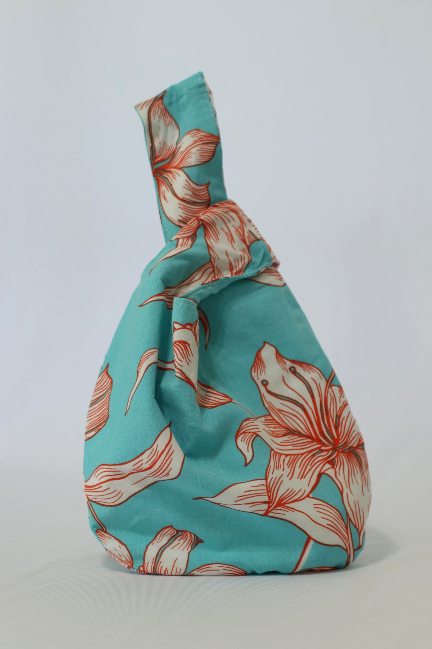 Knot Bag de Belemental con estampado floral en tonos turquesa y coral, de diseño único y sostenible.
