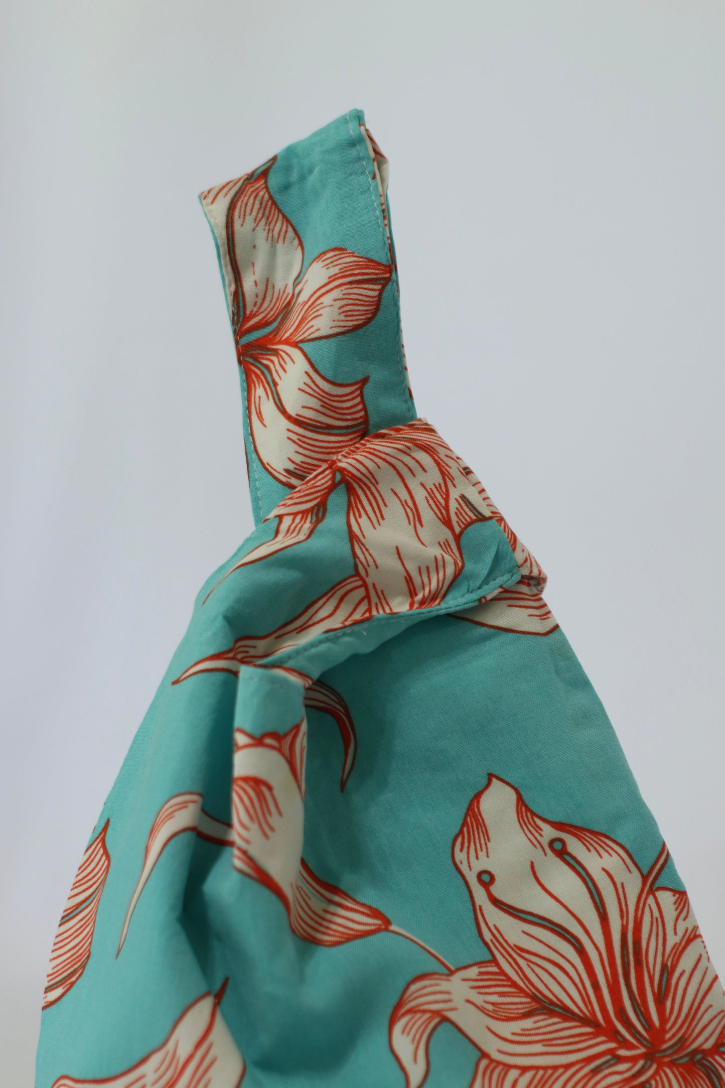 Knot Bag de Belemental, cómoda asa a la muñeca con estampado floral en tonos turquesa y coral.