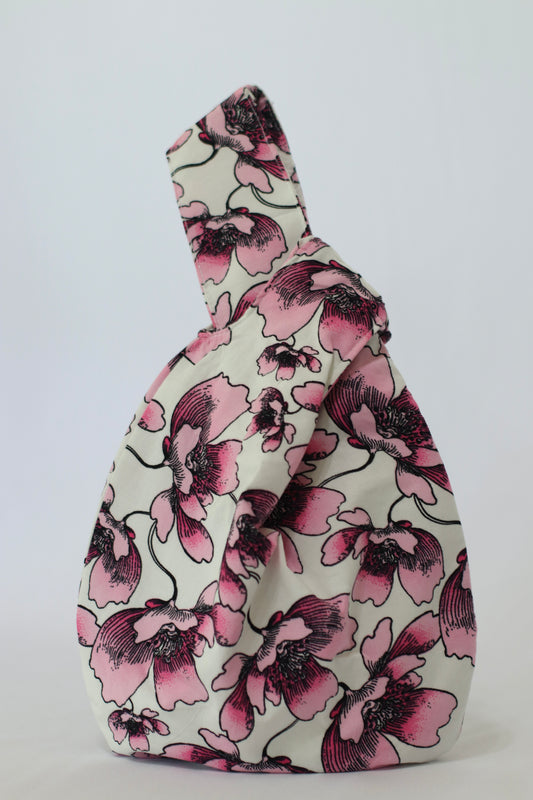 Knot Bag con estampado floral de grandes flores en tonos rosados y lilas y detalles en negro sobre fondo claro.
